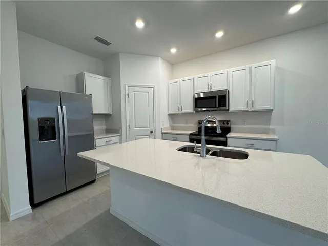 a kitchen with kitchen island a refrigerator sink and microwave