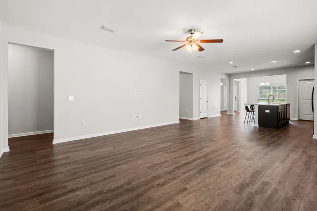 a view of an empty room with wooden floor and windows