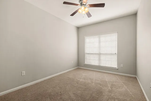 an empty room with a window and a fan