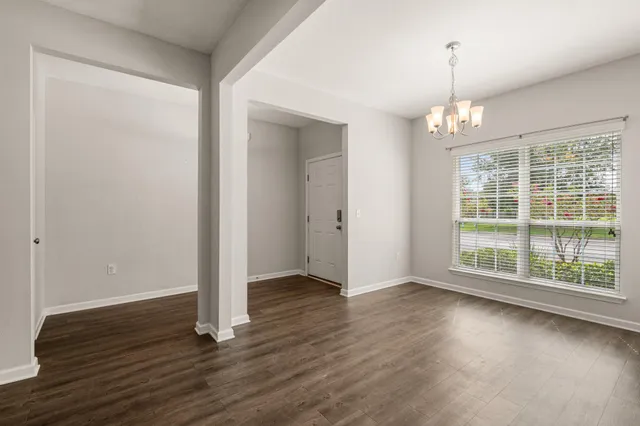 an empty room with wooden floor and large windows