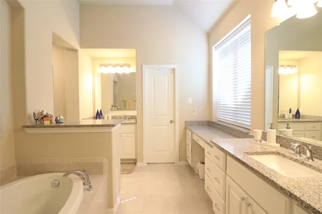 a bathroom with a granite countertop tub sink and mirror