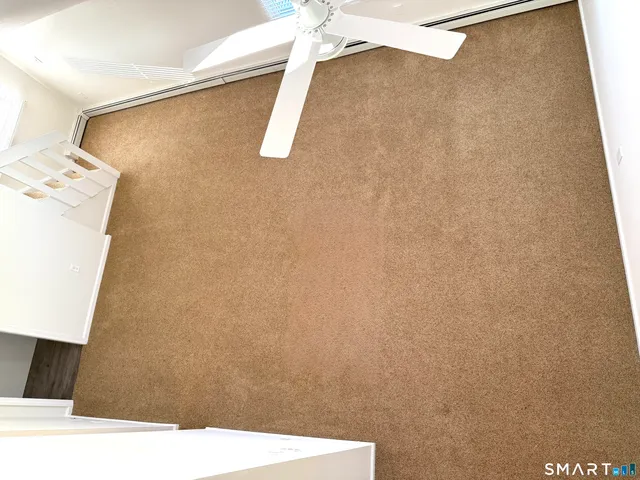 an empty room with a chandelier fan and windows