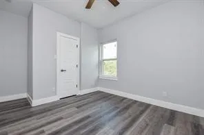 an empty room with wooden floor cabinet and windows