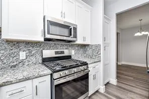 a kitchen with granite countertop a stove and a microwave