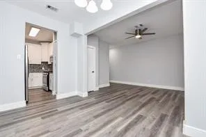 a view of an empty room with wooden floor and a ceiling fan
