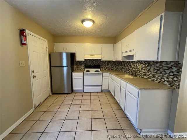 a kitchen with a refrigerator a stove top oven and cabinets