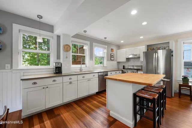 a large kitchen with stainless steel appliances granite countertop a stove a sink dishwasher and a refrigerator with wooden floor