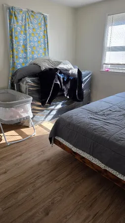a bedroom with a bed wooden floor and window