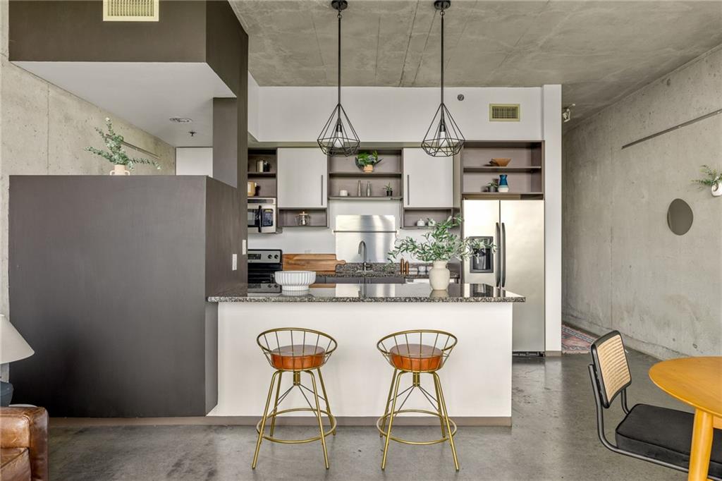 480 John Wesley Dobbs Avenue Northeast, Unit 612 Atlanta, GA 30312 - Photo 6 of 33 a kitchen with stainless steel appliances kitchen island granite countertop a table and chairs in it