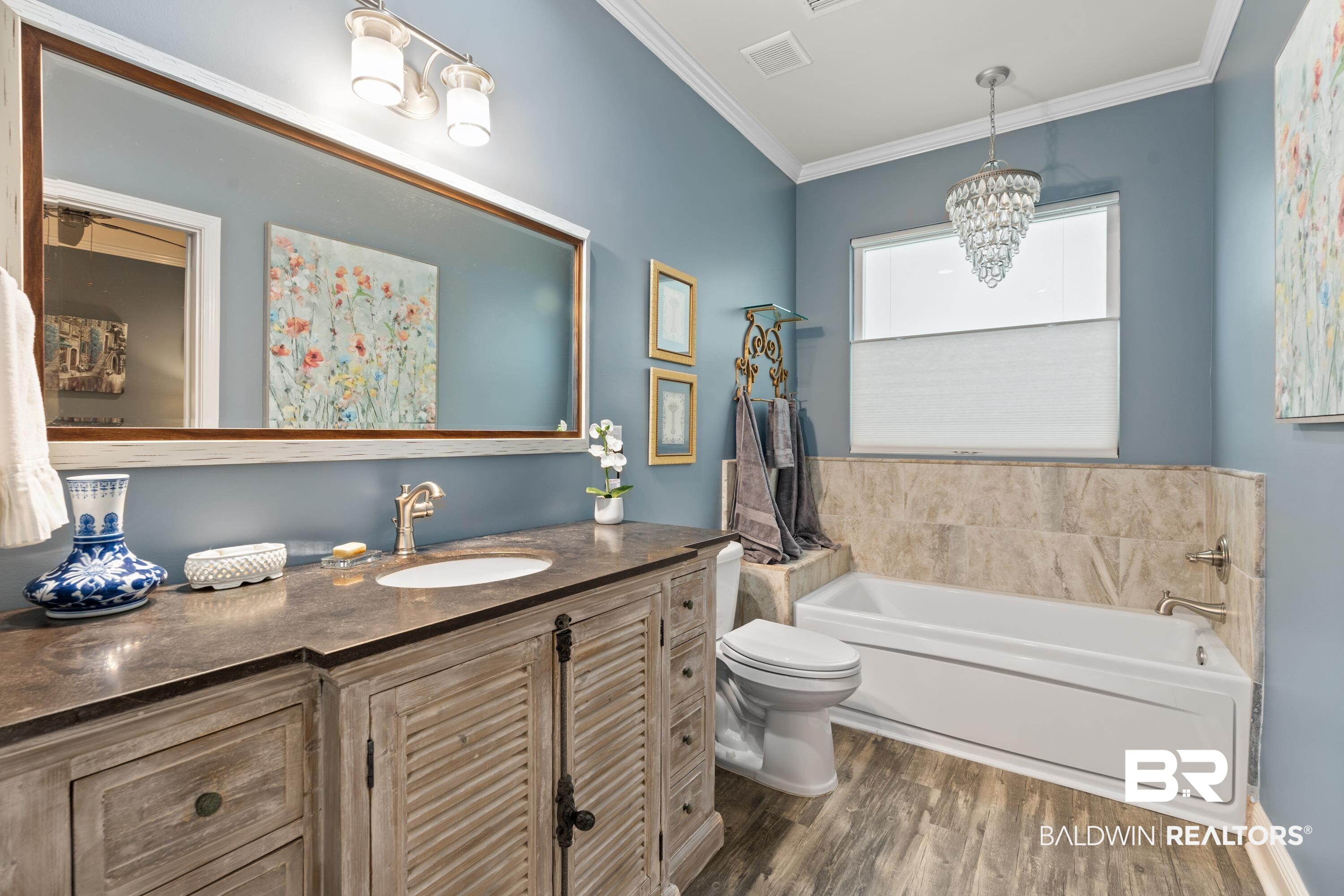 1113 Yellow Daisy Lane Foley, AL 36535 - Photo 19 of 35 Bathroom featuring a bath, wood finished floors, ornamental molding, vanity, and a chandelier