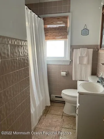 a bathroom with a toilet a sink a window and a shower