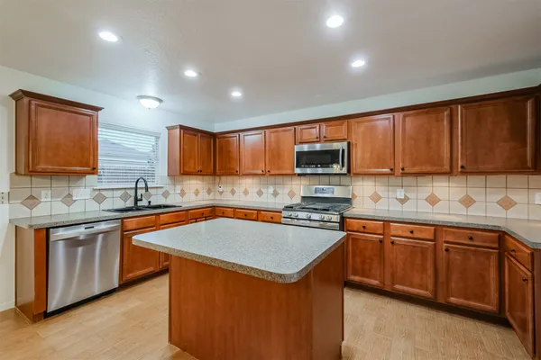 a kitchen with stainless steel appliances granite countertop wooden cabinets a sink and a stove