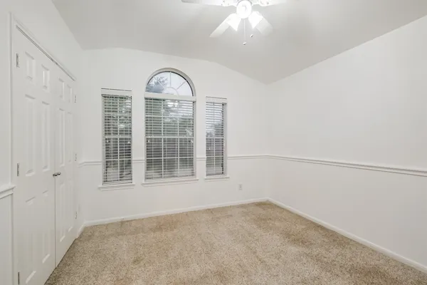 an empty room with a fan & a ceiling fan