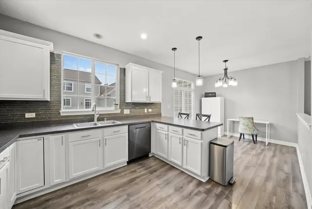 a large kitchen with granite countertop a white stove top oven a sink and dishwasher with wooden floor