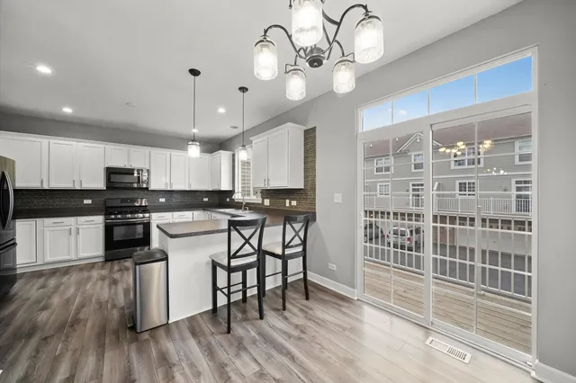 a kitchen with a dining table chairs wooden floor and appliances