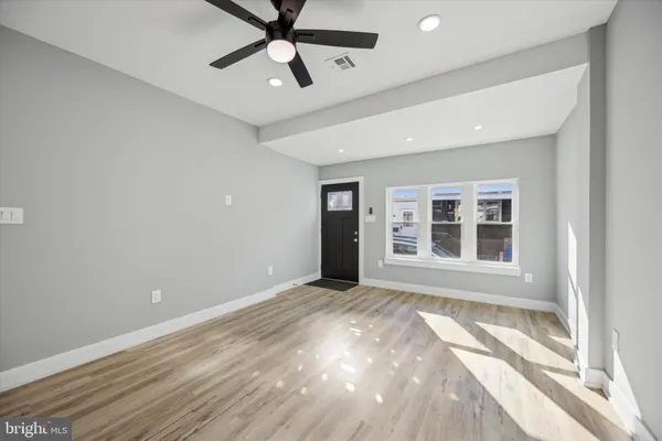an empty room with wooden floor ceiling fan and windows