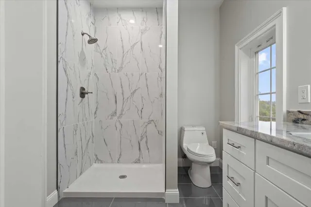a bathroom with a granite countertop sink a toilet and shower
