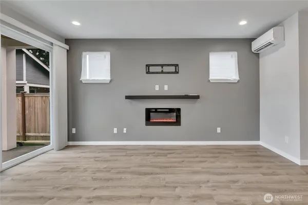 a view of an empty room with wooden floor and windows