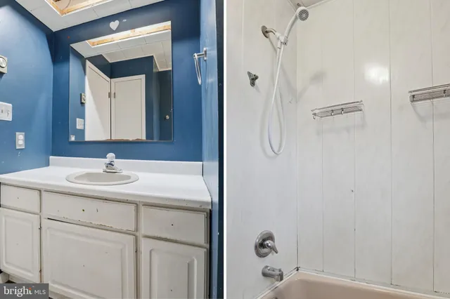 a bathroom with a granite countertop sink a mirror and shower