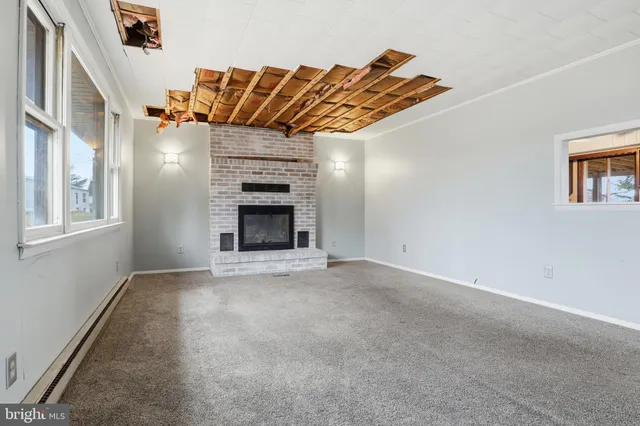 an empty room with windows and fireplace