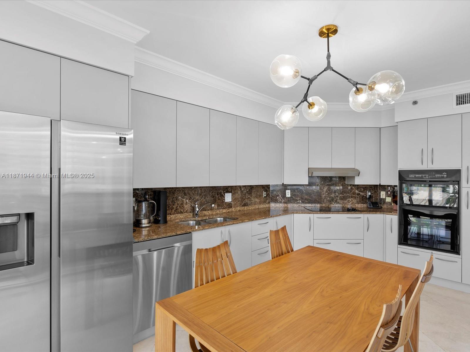 19111 Collins Avenue, Unit 1406 Sunny Isles Beach, FL 33160 - Photo 14 of 40 a kitchen with stainless steel appliances a stove center island a refrigerator and cabinets