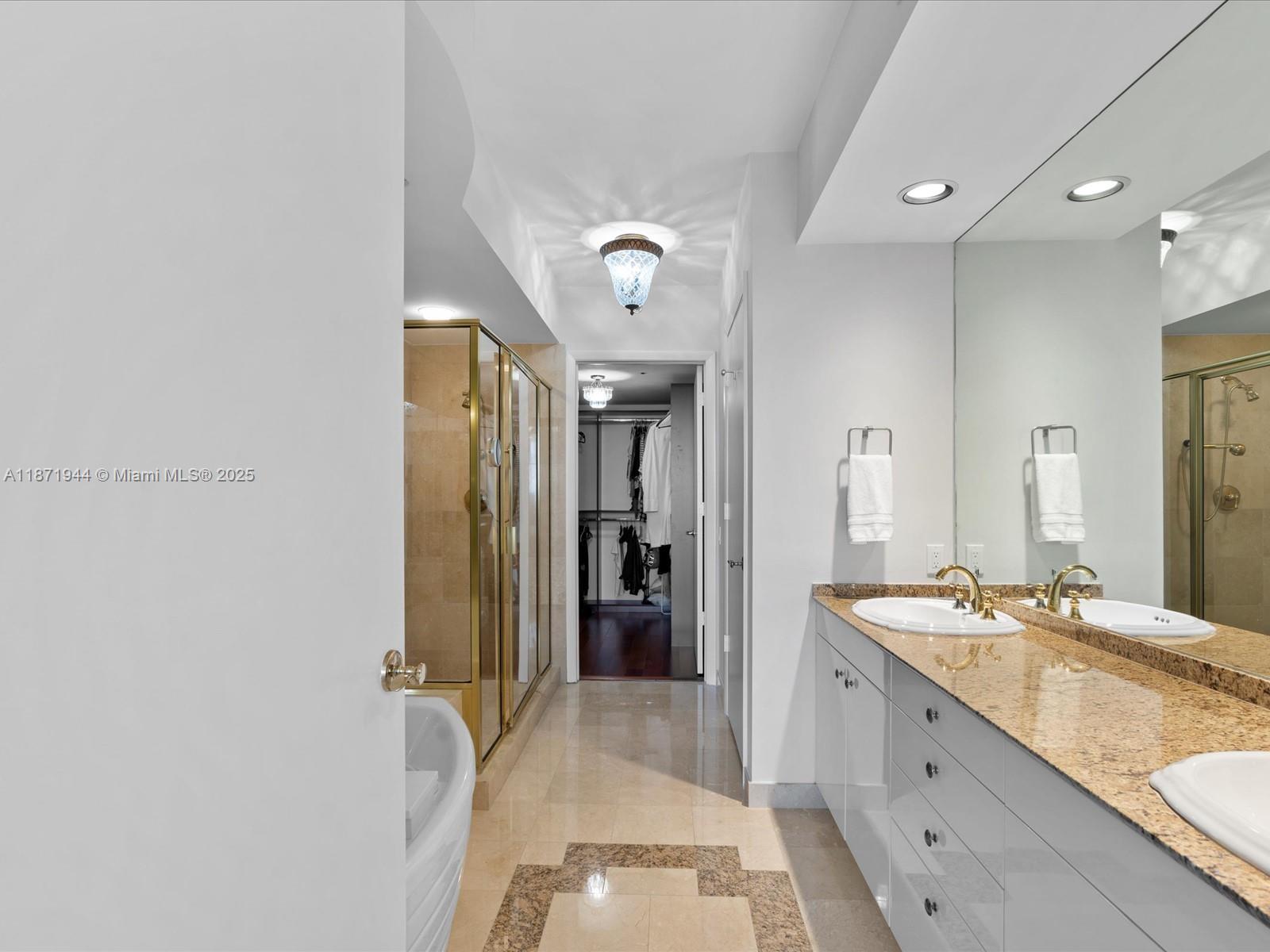 19111 Collins Avenue, Unit 1406 Sunny Isles Beach, FL 33160 - Photo 22 of 40 a spacious bathroom with a granite countertop sink a mirror and shower