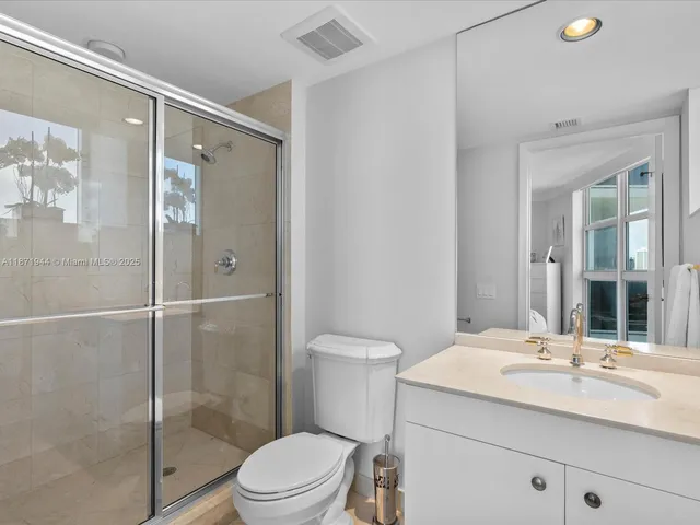 a bathroom with a shower sink vanity mirror and toilet