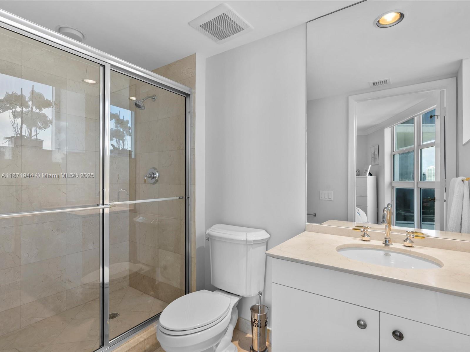 19111 Collins Avenue, Unit 1406 Sunny Isles Beach, FL 33160 - Photo 26 of 40 a bathroom with a shower sink vanity mirror and toilet
