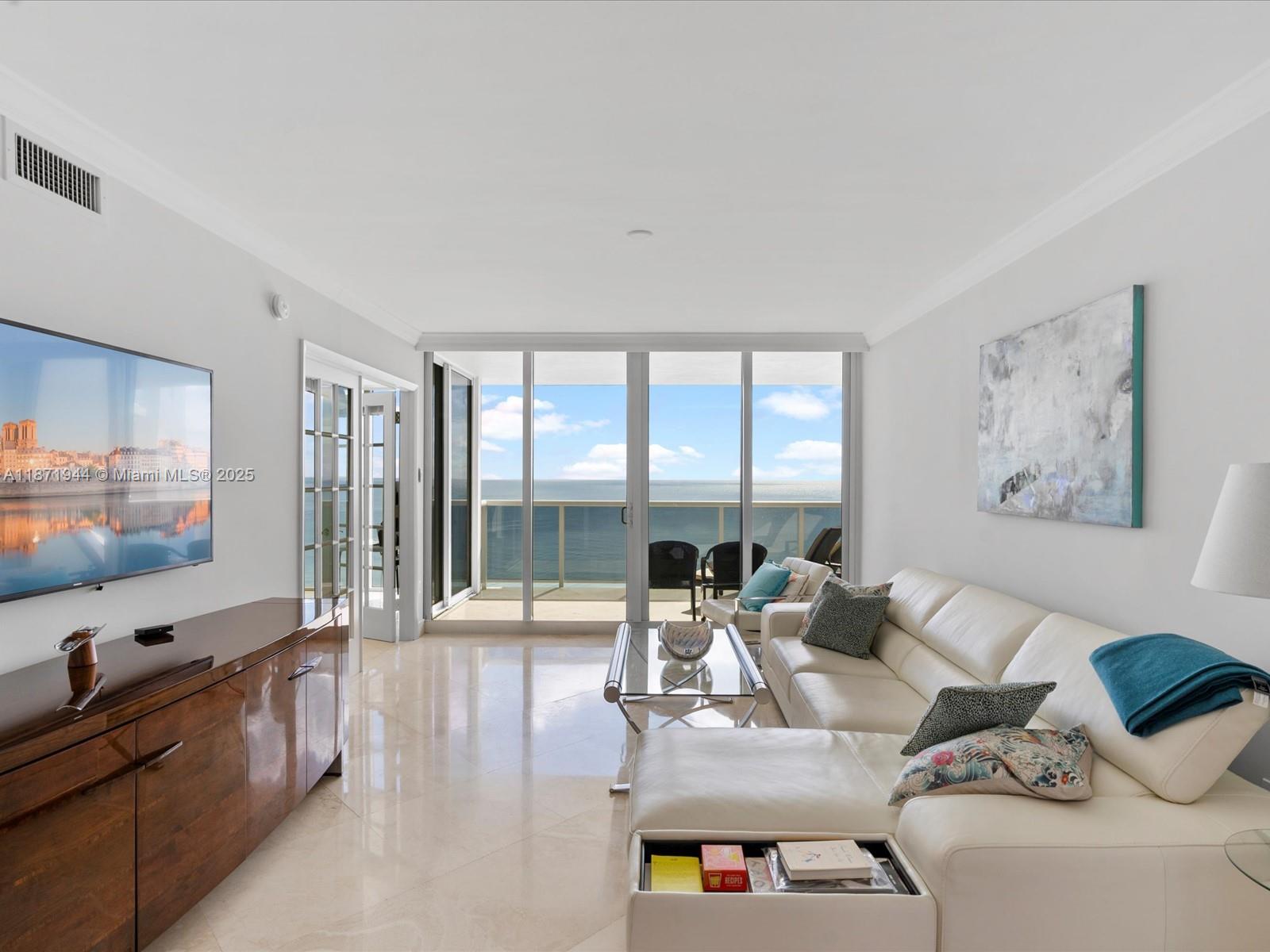 19111 Collins Avenue, Unit 1406 Sunny Isles Beach, FL 33160 - Photo 5 of 40 a living room with furniture and a flat screen tv