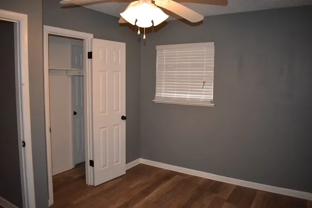 a view of an empty room with wooden floor and a window