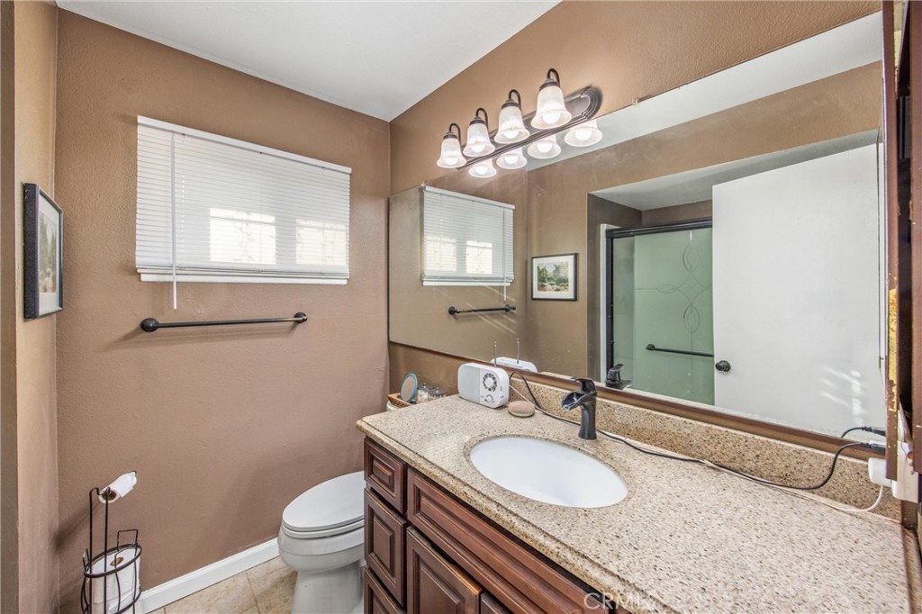 10399 Monte Vista Street Rancho Cucamonga, CA 91701 - Photo 31 of 43 a bathroom with a granite countertop double vanity sink mirror and toilet