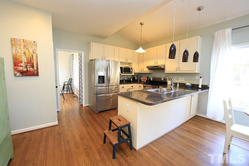 4100 Stemmons Court Raleigh, NC 27613 - Photo 4 of 13 a kitchen with stainless steel appliances granite countertop a refrigerator a stove a sink and white cabinets with wooden floor