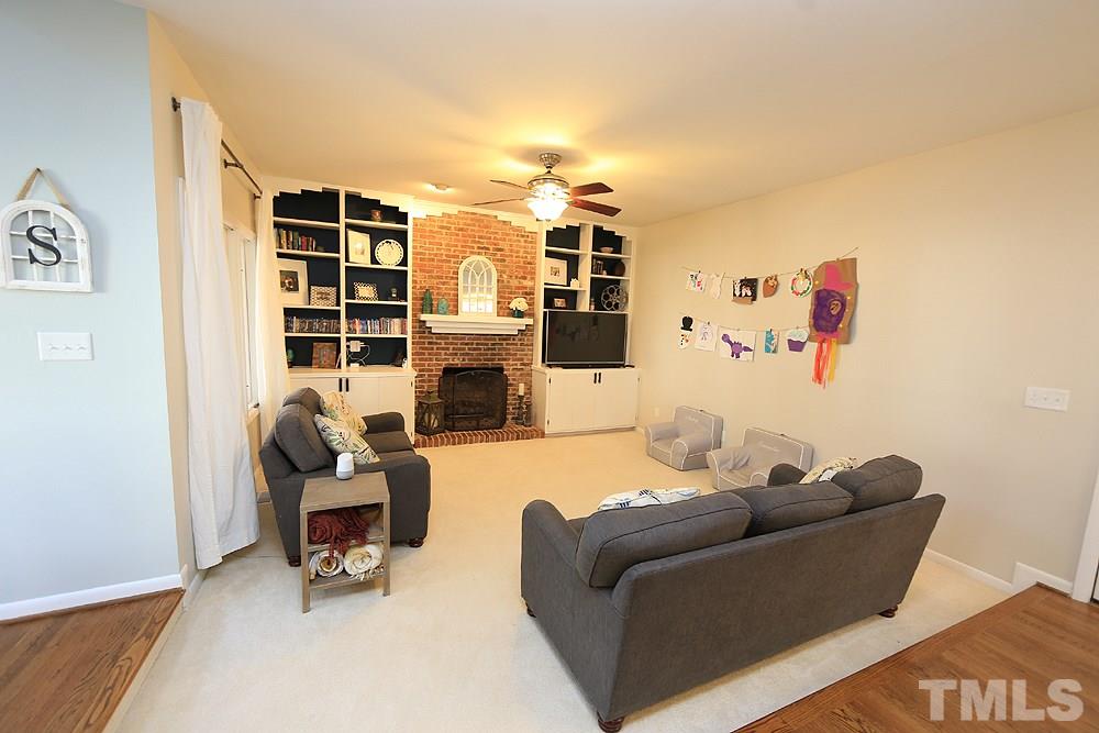 4100 Stemmons Court Raleigh, NC 27613 - Photo 6 of 13 a living room with furniture a fireplace and a book shelf