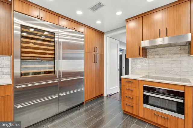 a kitchen with stainless steel appliances kitchen island granite countertop a refrigerator and a stove top oven