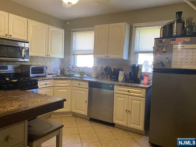 a kitchen with stainless steel appliances granite countertop a sink stove refrigerator and cabinets