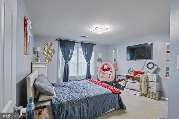 a bedroom with bed and a flat tv screen on dresser