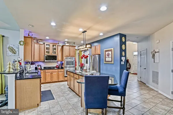 a kitchen with stainless steel appliances granite countertop a sink dishwasher a stove and a refrigerator with wooden floor