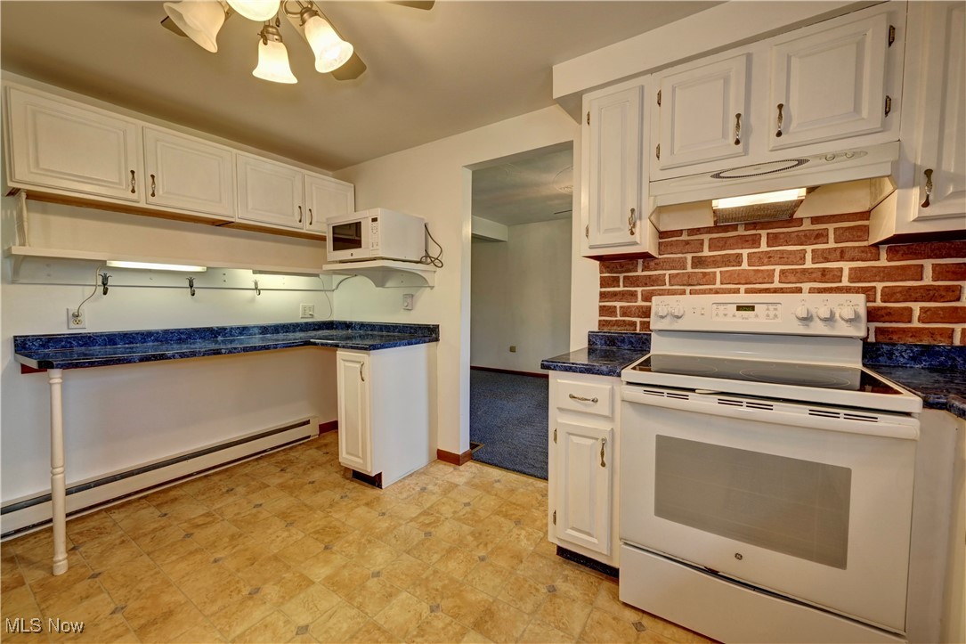 48846 Cain Ridge Road Clarington, OH 43915 - Photo 20 of 45 Kitchen with white appliances, under cabinet range hood, a ceiling fan, and dark countertops