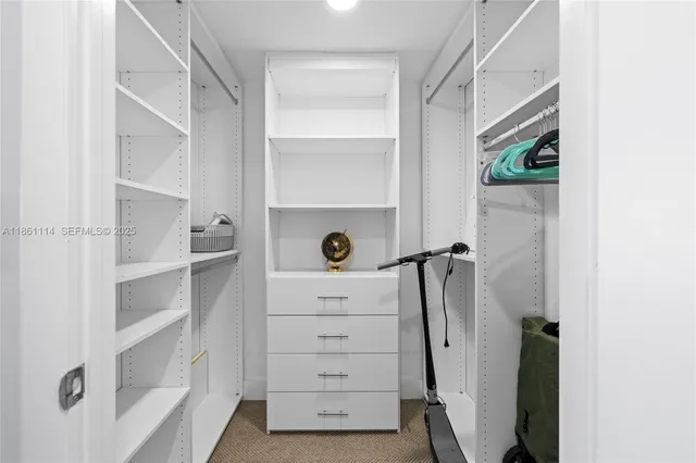 a view of walk in closet with clothes and shoes