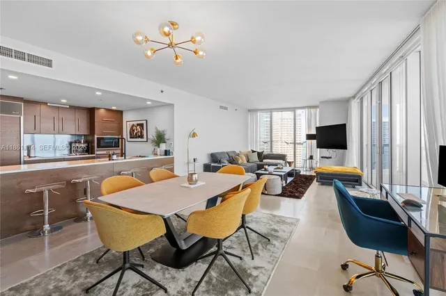 a living room with furniture kitchen view and a large window