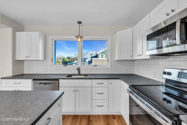 a kitchen with stainless steel appliances granite countertop a sink a stove and a microwave