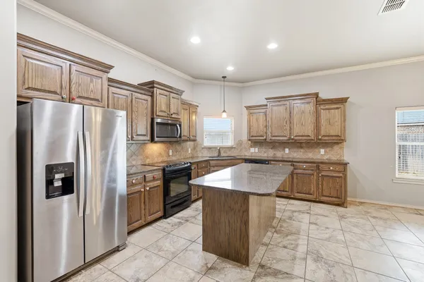 a kitchen with granite countertop a refrigerator stove top oven and sink