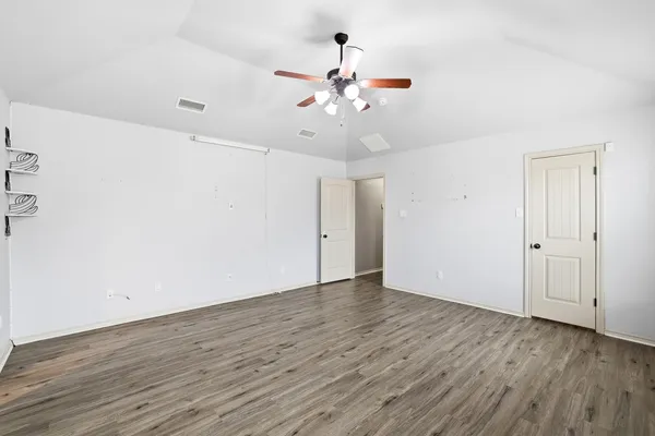 an empty room with wooden floor fan and window