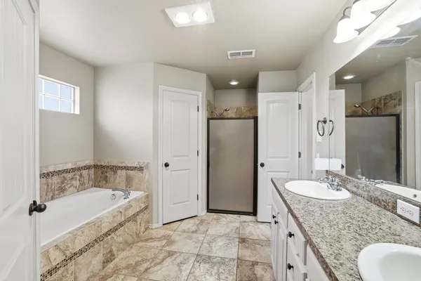 a spacious bathroom with a granite countertop tub sink shower and mirror