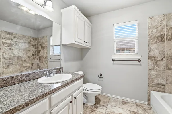 a bathroom with a granite countertop sink toilet and a mirror