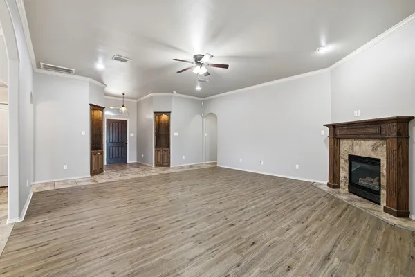 a view of an empty room with wooden floor fireplace and a window