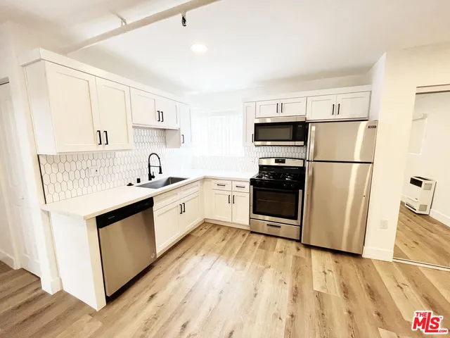 a kitchen with white cabinets and stainless steel appliances