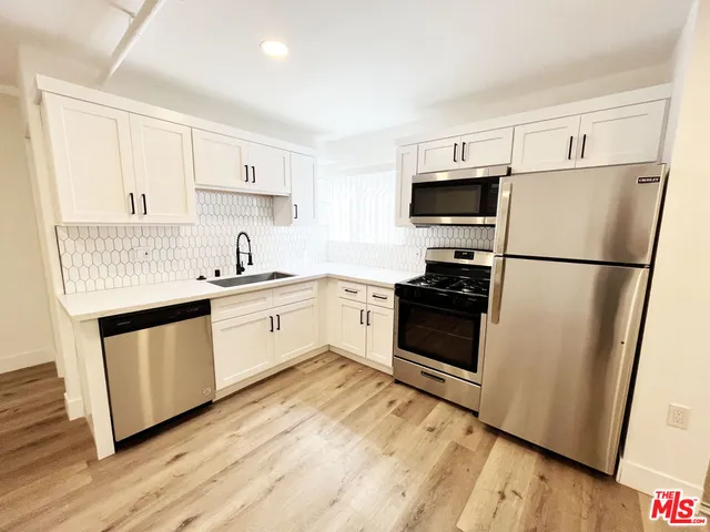 a kitchen with a refrigerator sink and wooden floor