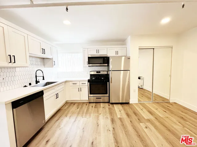 a kitchen with stainless steel appliances granite countertop a refrigerator sink and white cabinets