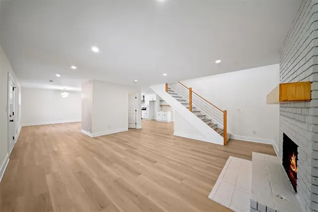 a view of an empty room with wooden floor and a fireplace